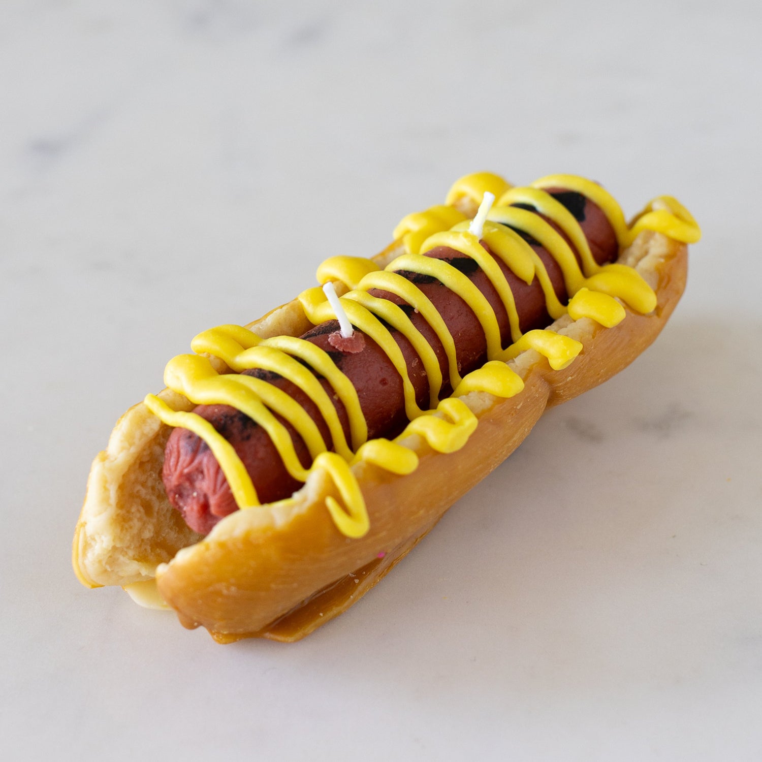 Hot Dog Candle with a bun and mustard on top.