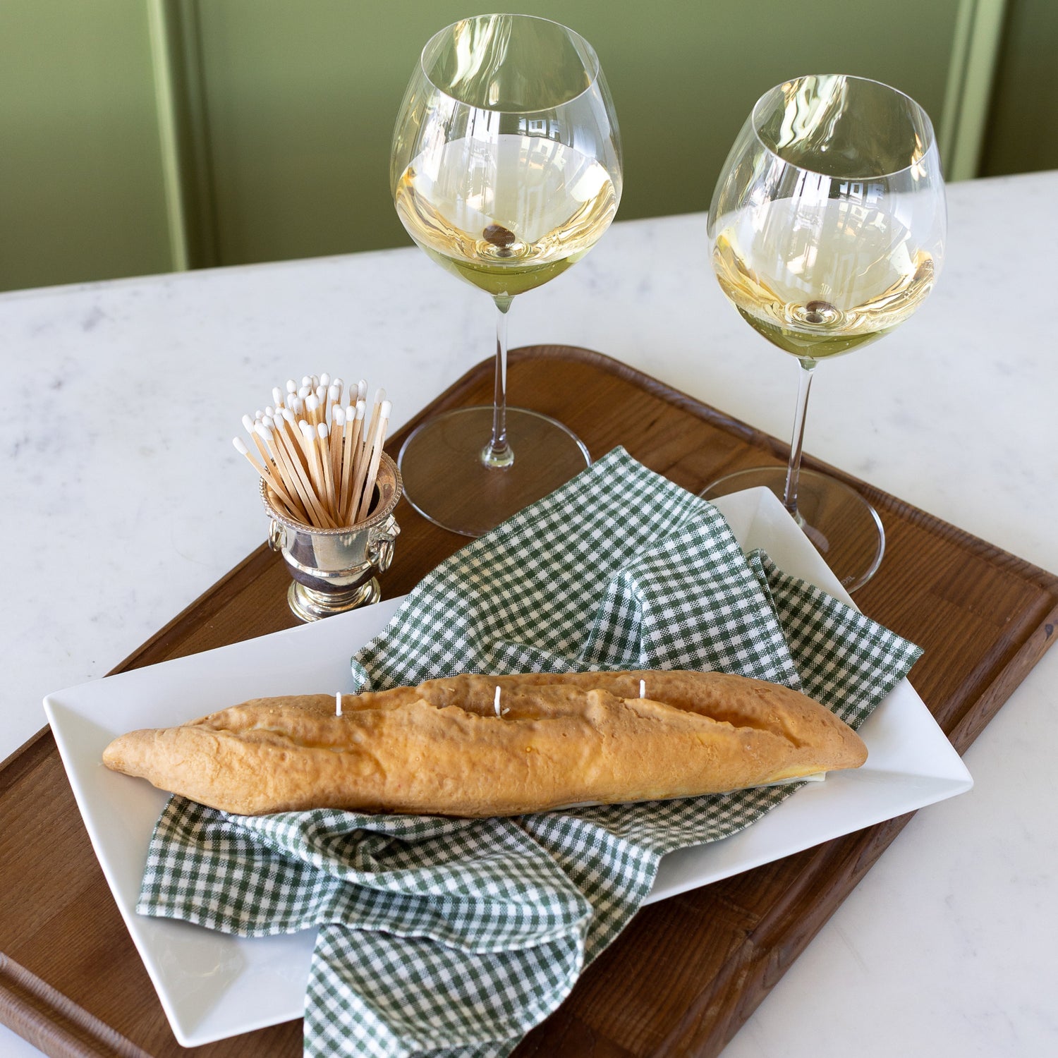 Baguette Candle on a plate, styled on a wood board with wine glasses and matches.