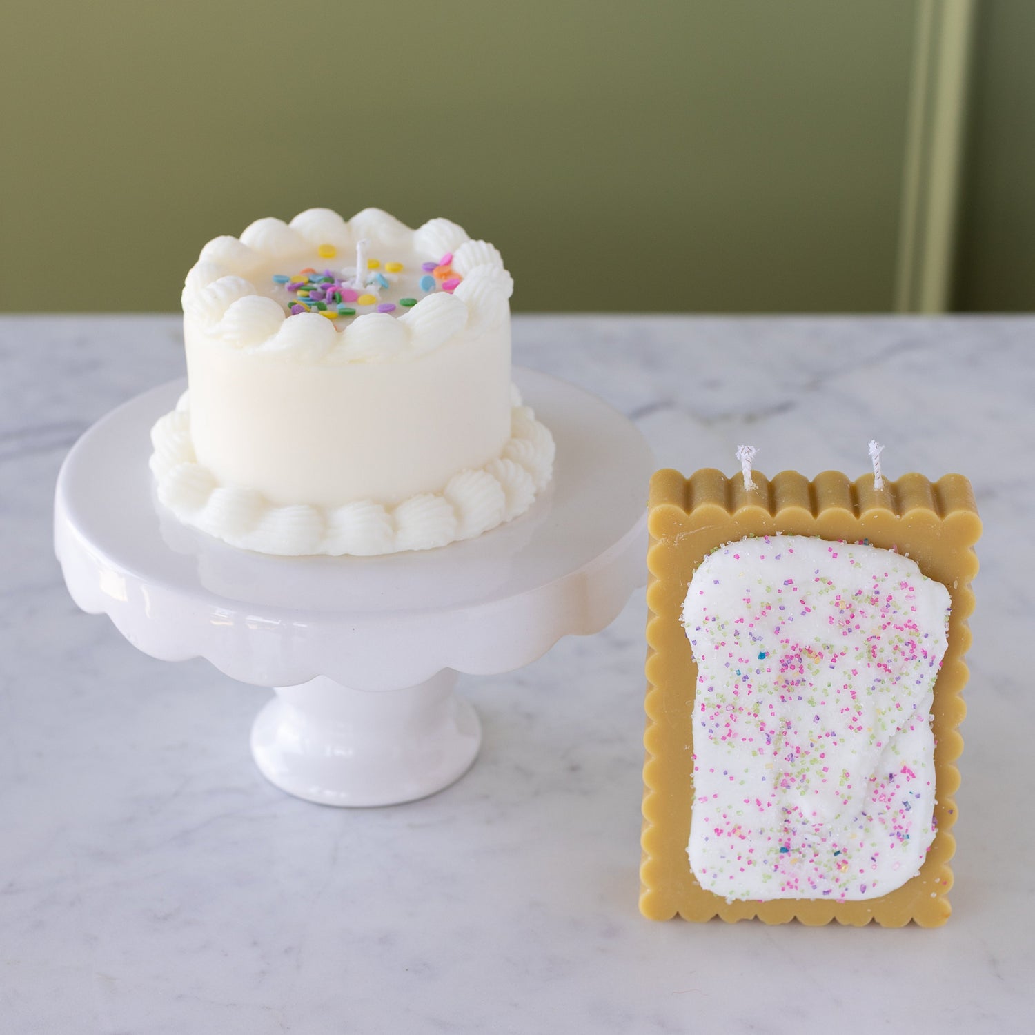 The Poptart Candle next to the Birthday Cake Candle on a mini pedestal stand.