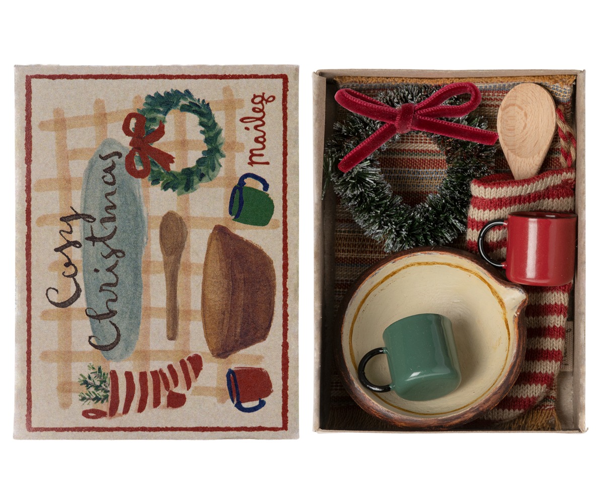 small stocking, rug, wreath, two cups and a bowl with a wooden spoon in box with top to the side