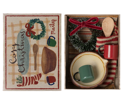 small stocking, rug, wreath, two cups and a bowl with a wooden spoon in box with top to the side