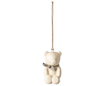 Off white metal teddy bear ornament with blue ribbon tied around its neck