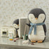 Penguin in a miniature kitchen setting, holding a mop, ready to clean up ice cream cones spilled by a smaller penguin peeking from behind the fridge.