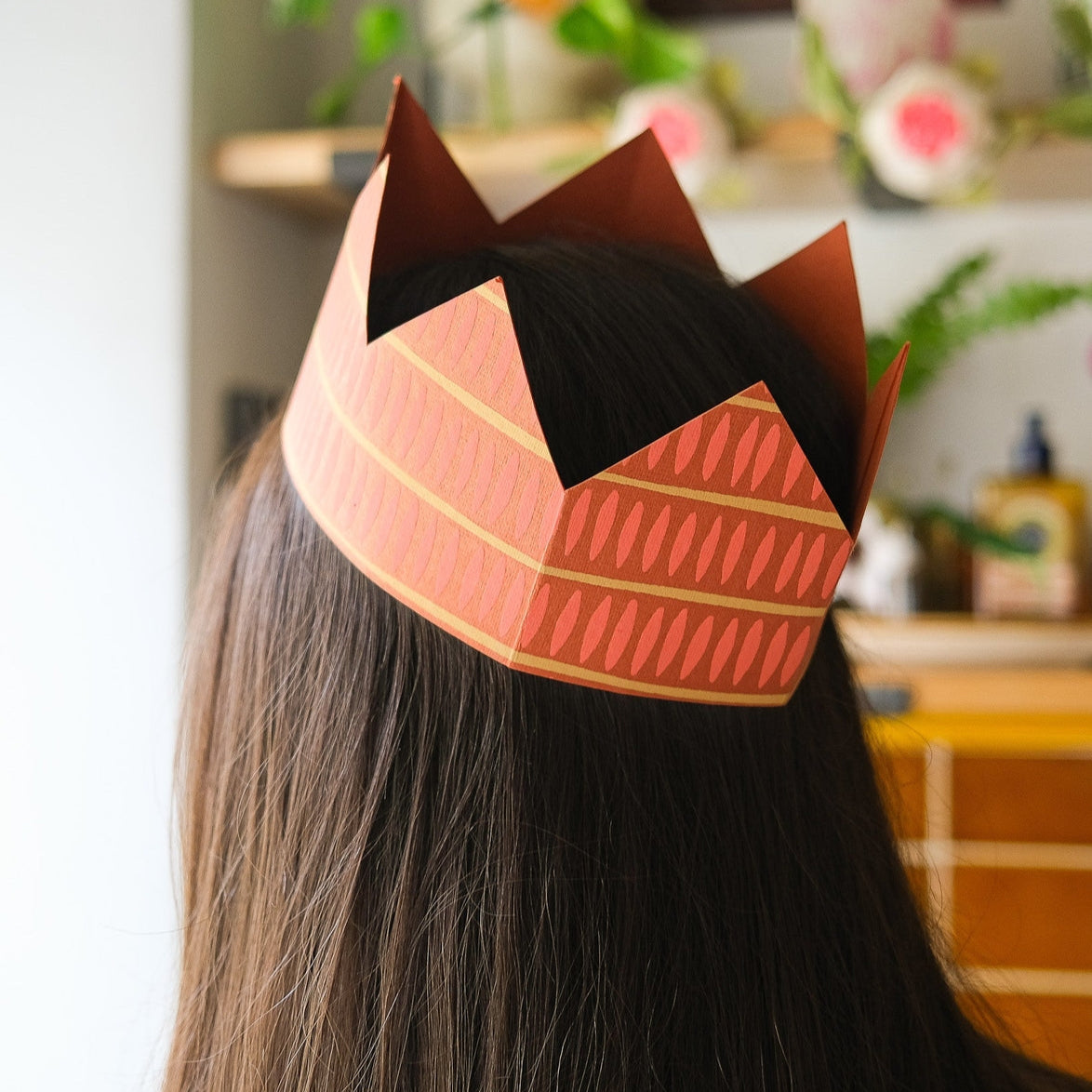 A woman wearing the East End Press Yellow Paper Party Crown on her head.