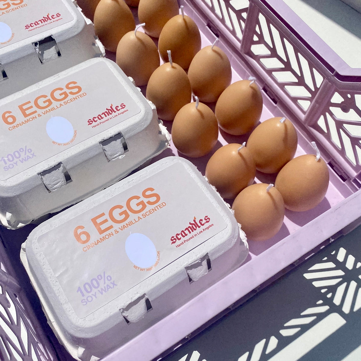 Sets of egg candles in their boxes as well as loose in a shopping basket. 