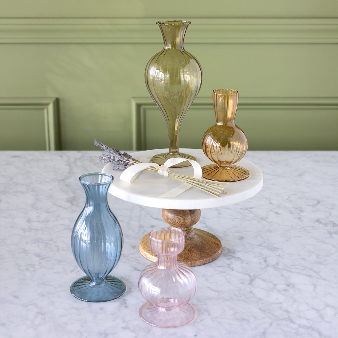 Vintage Boutique Vases on a table with some on a pedestal with a bundle of flowers.