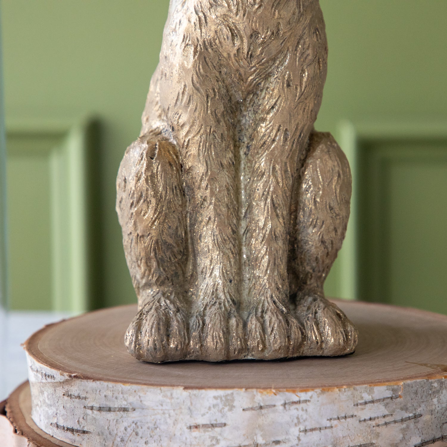 A close up of the feet of the Gold Leaf Rabbit in sitting position, on top of wood slices.