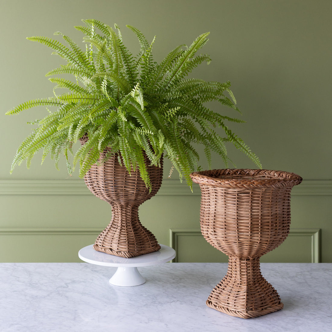  A Woven Urn on top of a cake stand with a Fern it in and an empty Woven Urn next to it.