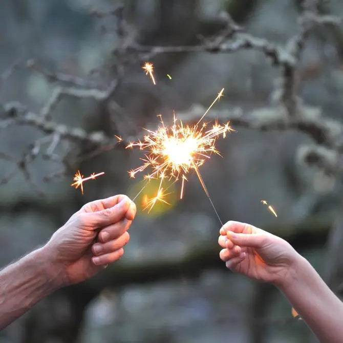 People holding 2 sparklers together. 