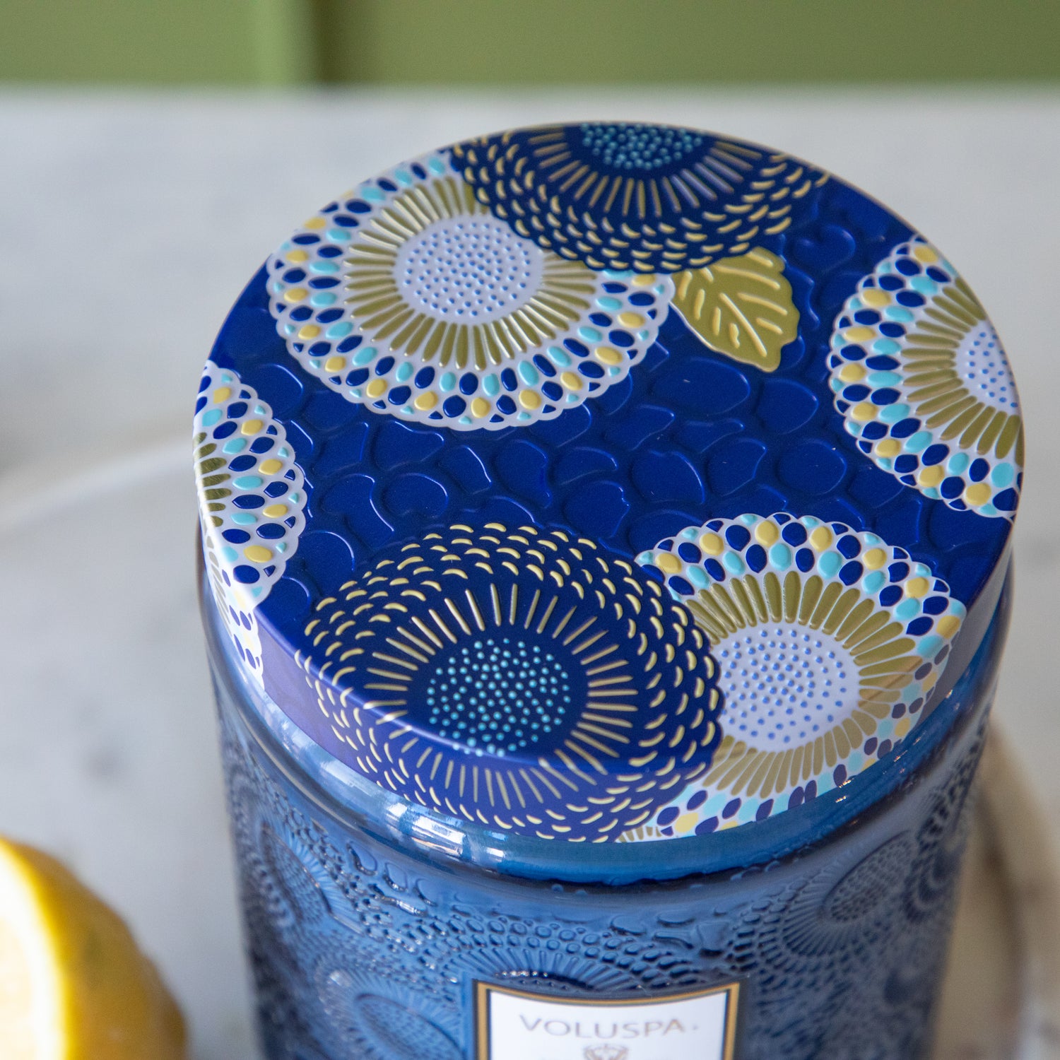 The lid of the Large Mediterranean Lemon Candle showing its colorful design of blues, golds and yellows in the glass.