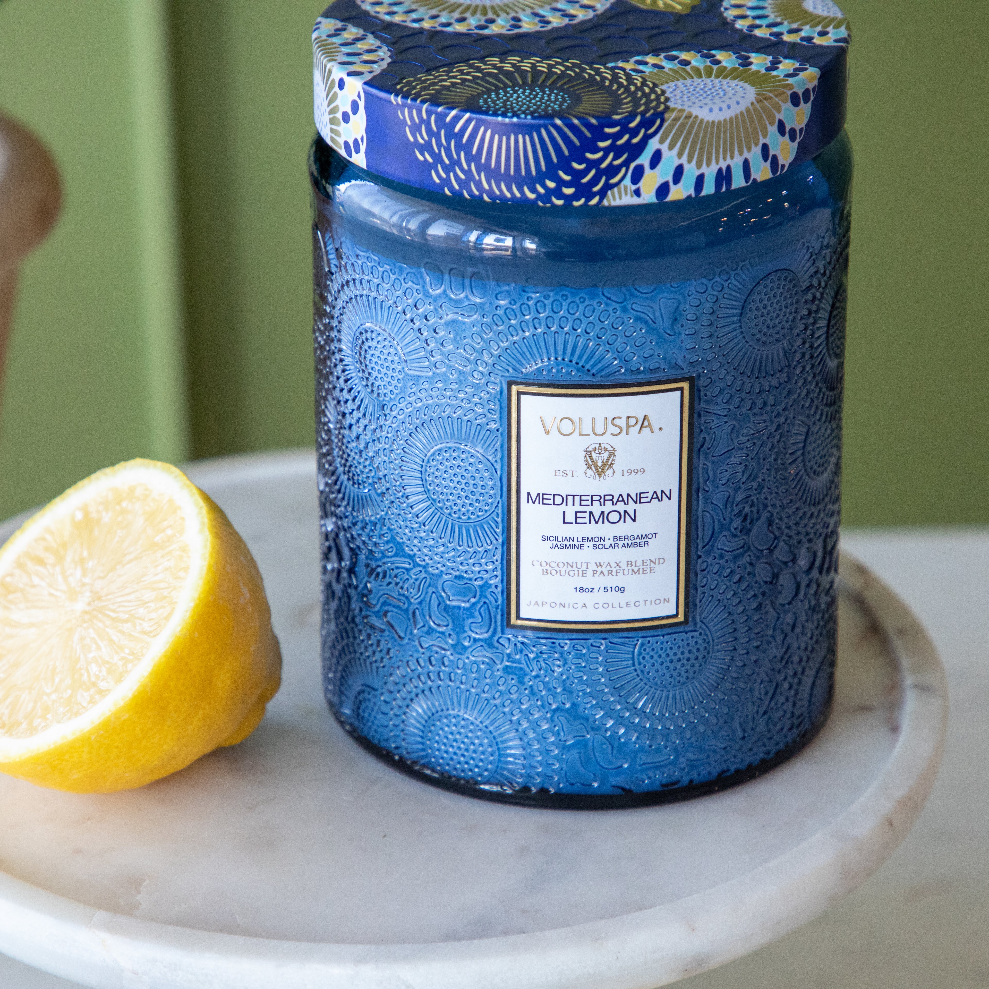 The large Mediterranean Lemon Candle next to a sliced lemon.