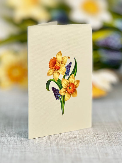 A potted arrangement of artificial orchids with a wooden stand against a white background, accompanied by a Fresh Cut Paper Mini Pop Up Flower Bouquet.