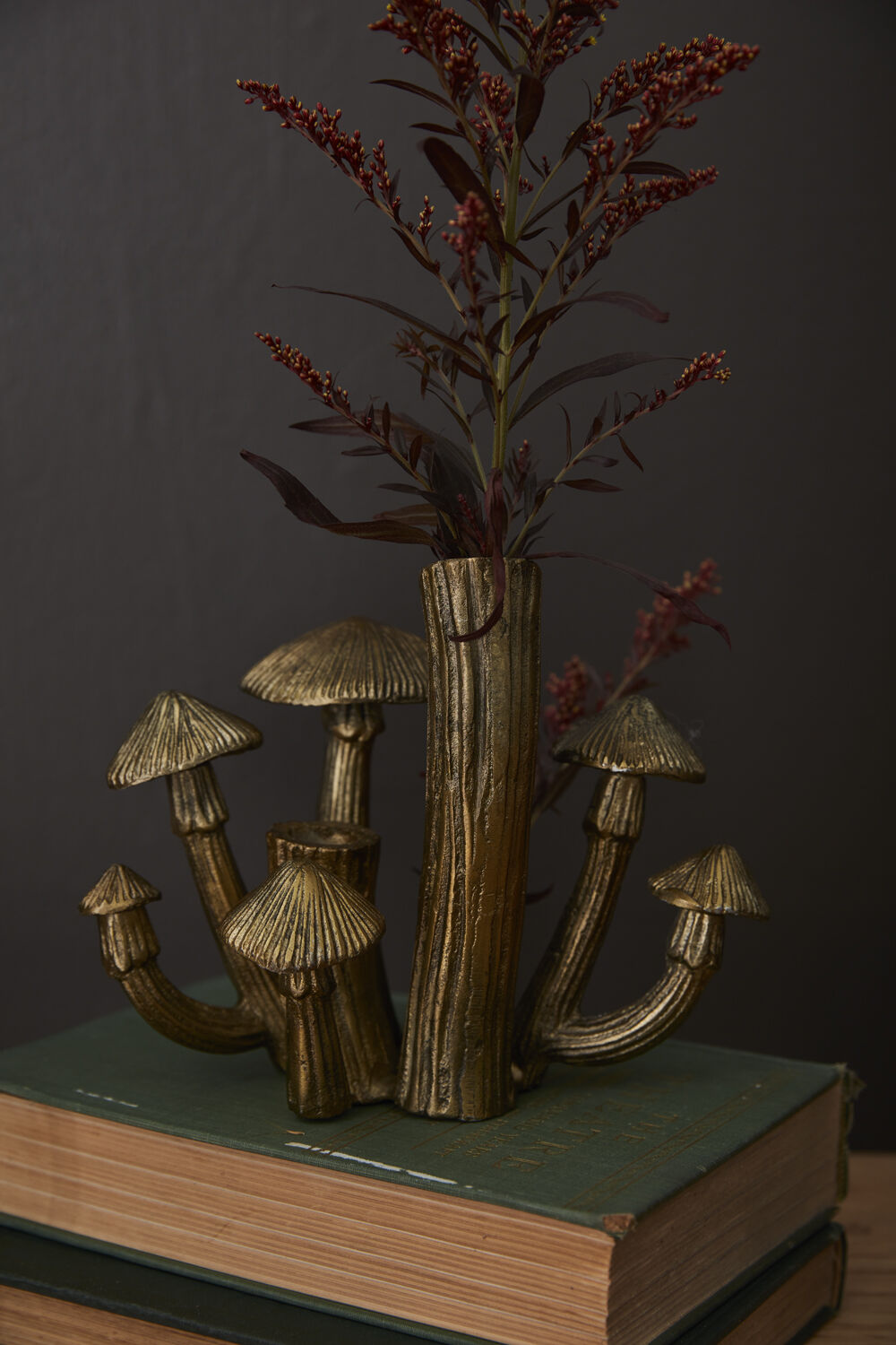 Brass Mushroom Cluster Budvase on a book with a plant in it.