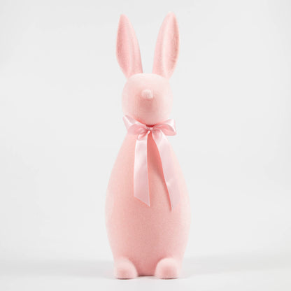 Pink flocked bunny with a pink bow tied around its neck. 