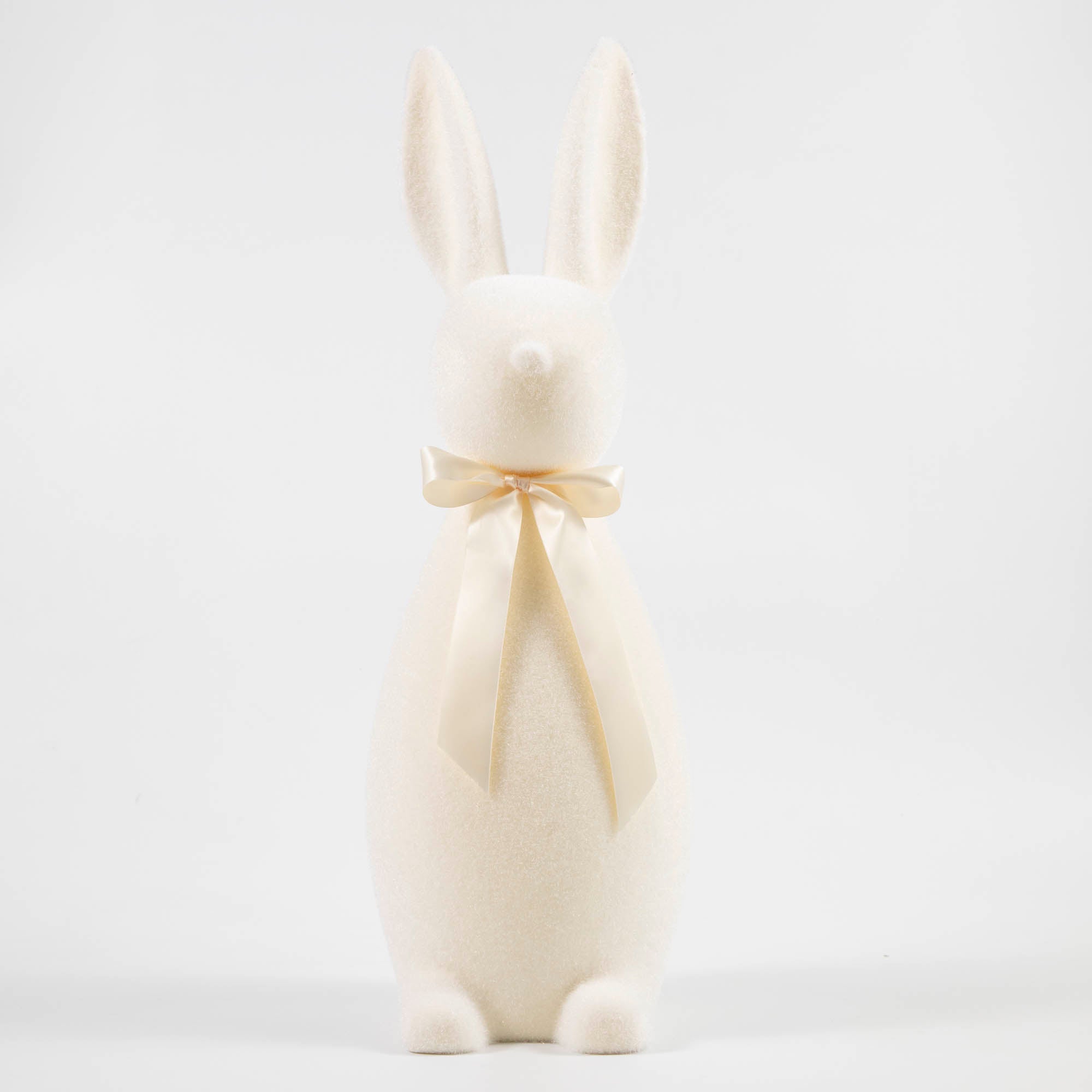 White flocked bunny with a pink bow tied around its neck. 