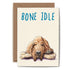 Greeting card featuring a hound dog sleeping on a bone with the pun "bone idle" written at the top in blue.