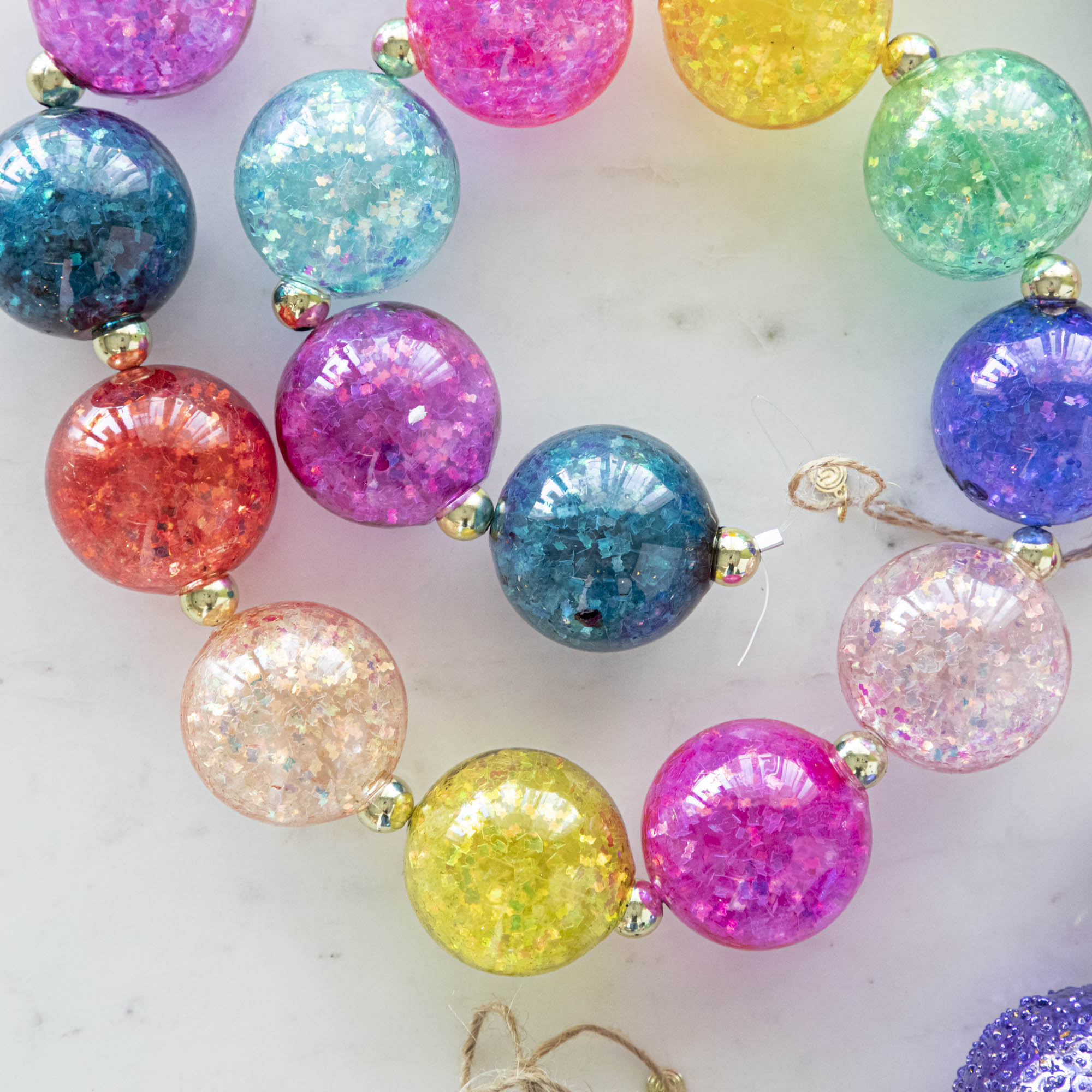 A colorful iridescent ball garland on a marble table.