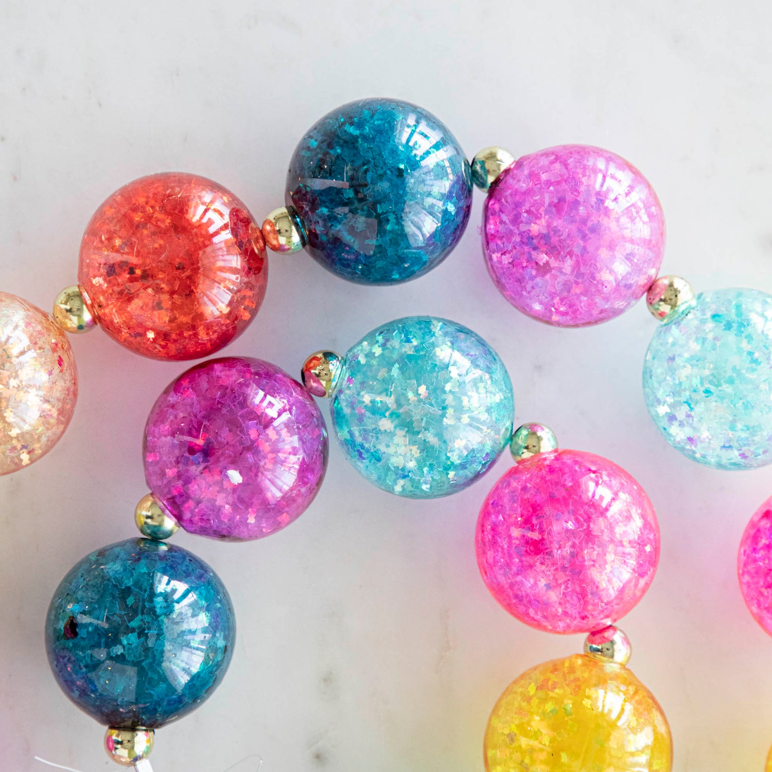 A colorful iridescent ball garland on a marble table.