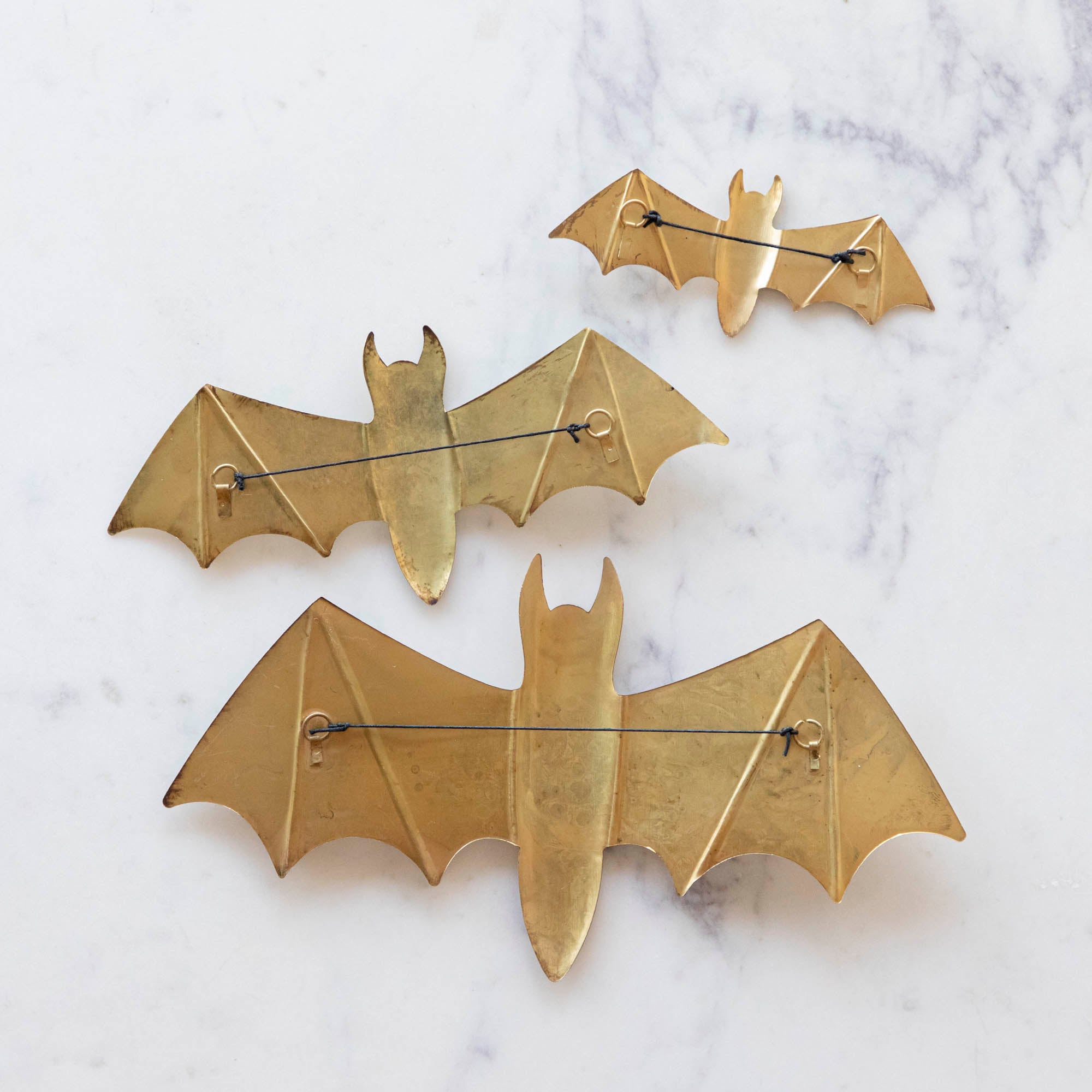 A small, medium and large metal winged bat backside with a string for hanging.