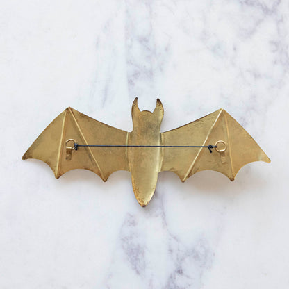 A medium gold metal winged bat back view featuring a string for hanging.