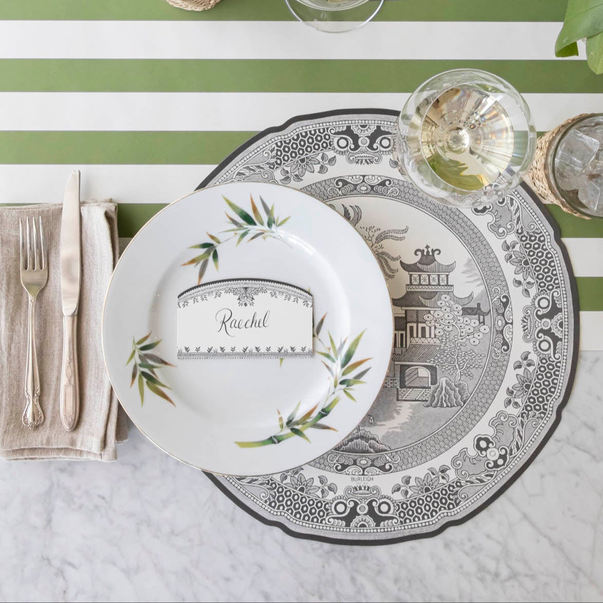 Die-cut Blue Willow Placemat on the Classic Moss Green Stripe Runner and a classic place setting on top.