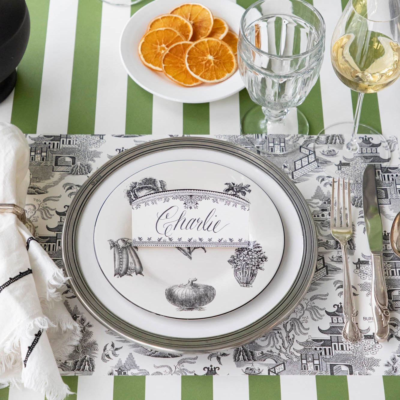 Black Willow Place Card with &quot;Charlie&quot; written on it, resting on dinner plates on an elegant place setting.