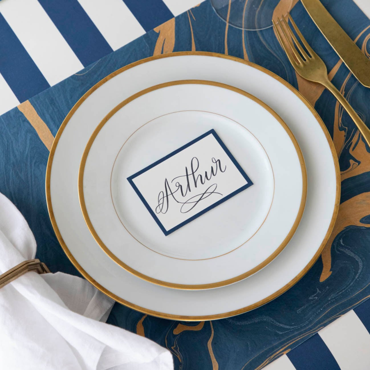 The Blue &amp; Gold Vein Marbled Placemat under an elegant place setting.