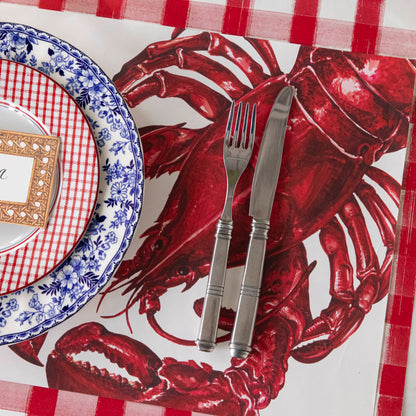 Maine Lobster Placemat on the Red Painted Check Runner with a place setting on top.