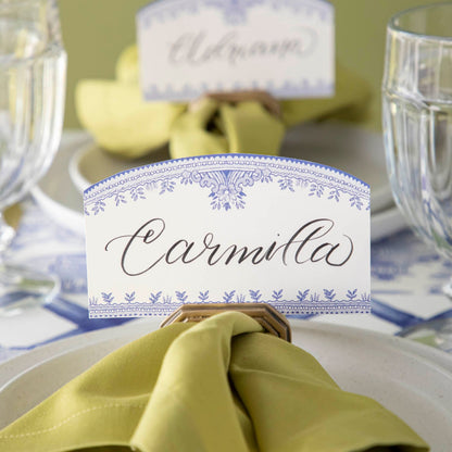 The Blue Willow Place card with &quot;Carmilla&quot; written in the white space, held up by the Brass Napkin Ring with Place Card Holder.