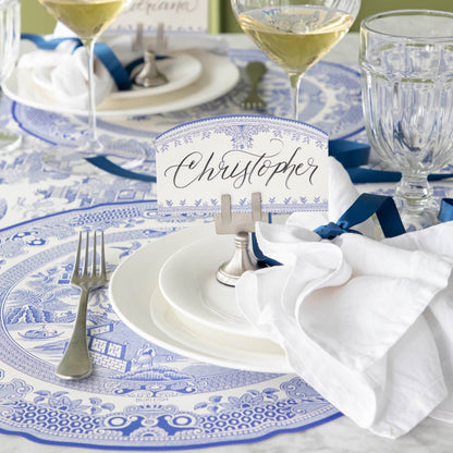 Burleigh Blue Place Card with &quot;Christopher&quot; written in the white space, held up by the Silver Place Card Holder on an elegantly styled dinner table.