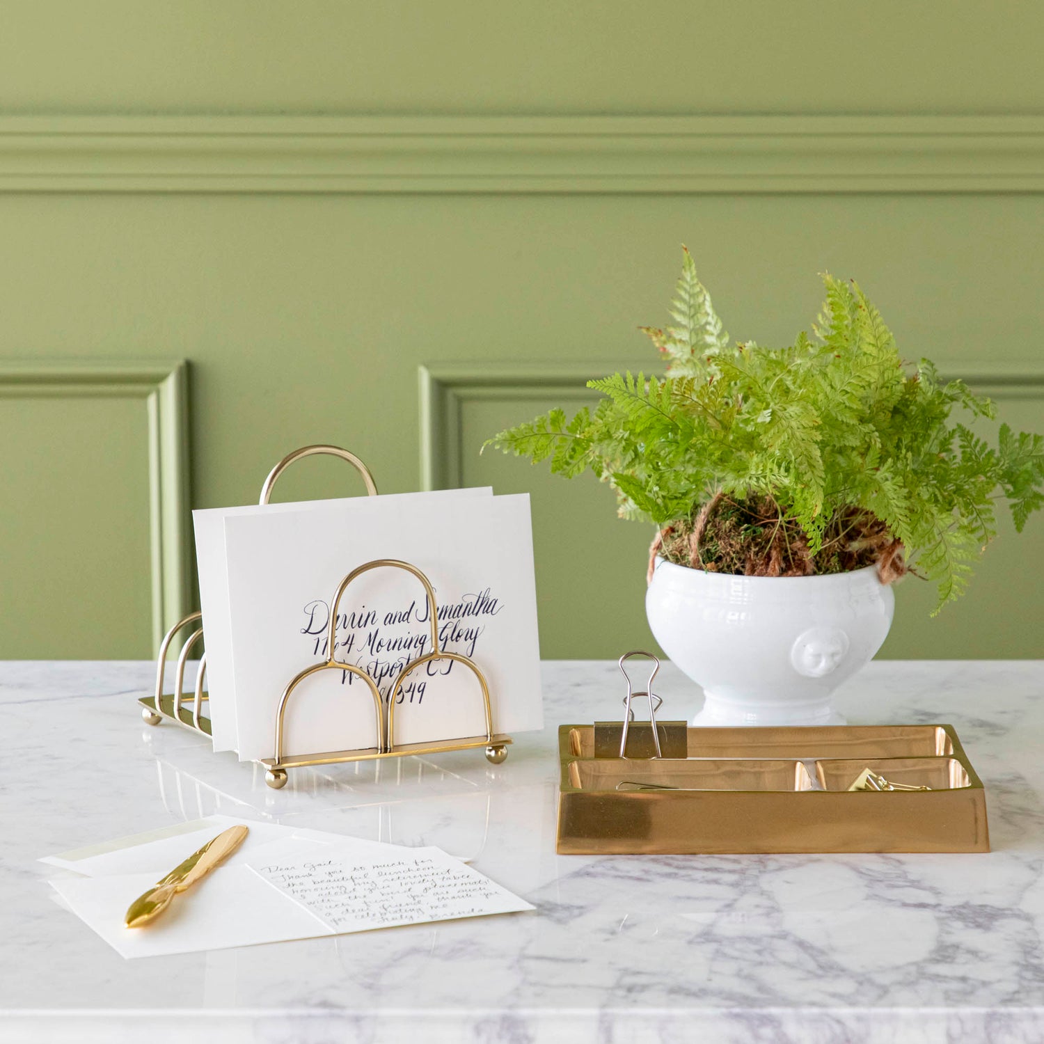 brass correspondence holder styled with various stationery accessories 