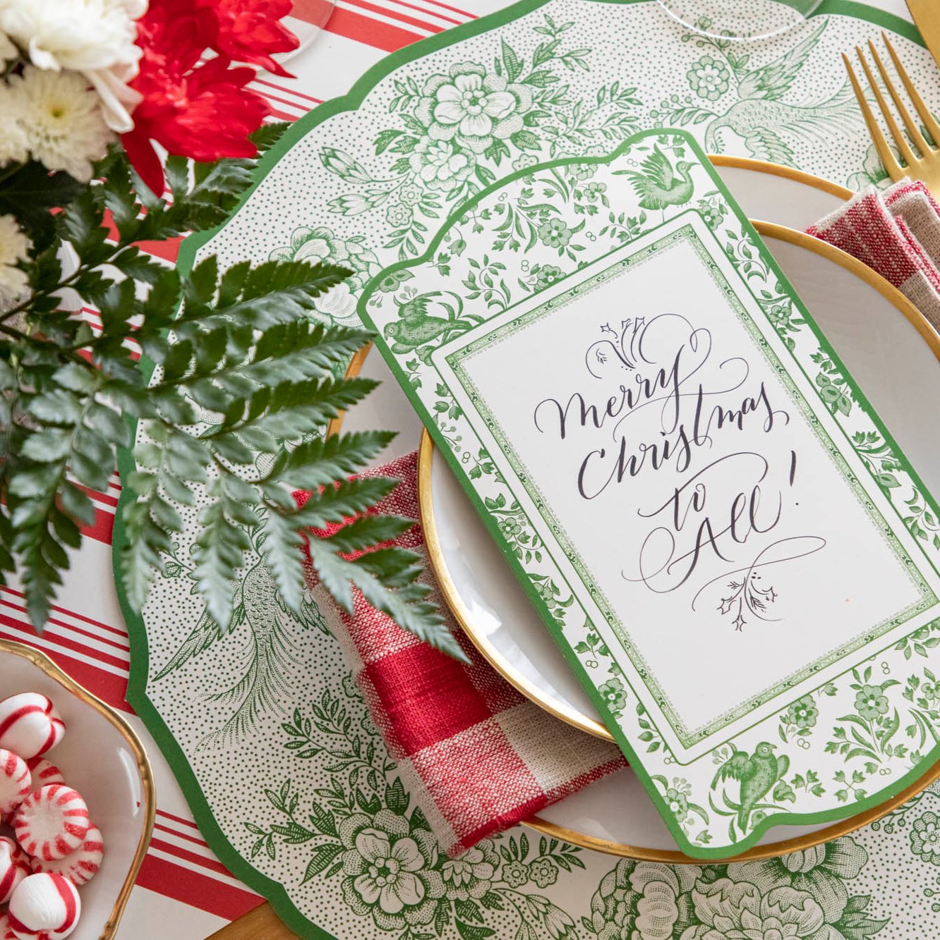 An elegant Christmas table setting featuring the Green Regal Peacock table card with &quot;Merry Christmas to All&quot; written on it in cursive.