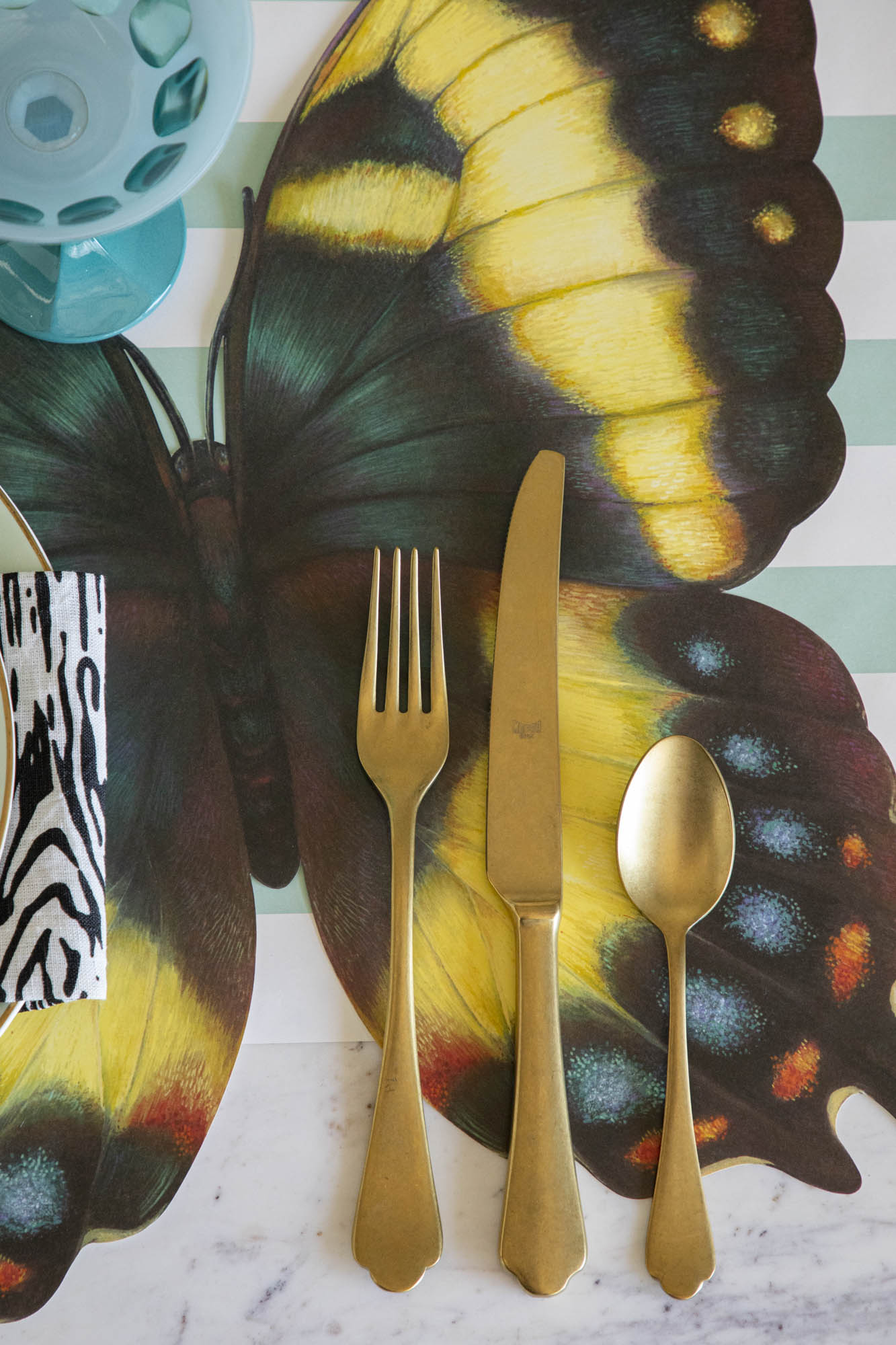 Close-up of a set of gold flatware on a Die-cut Butterfly Placemat.