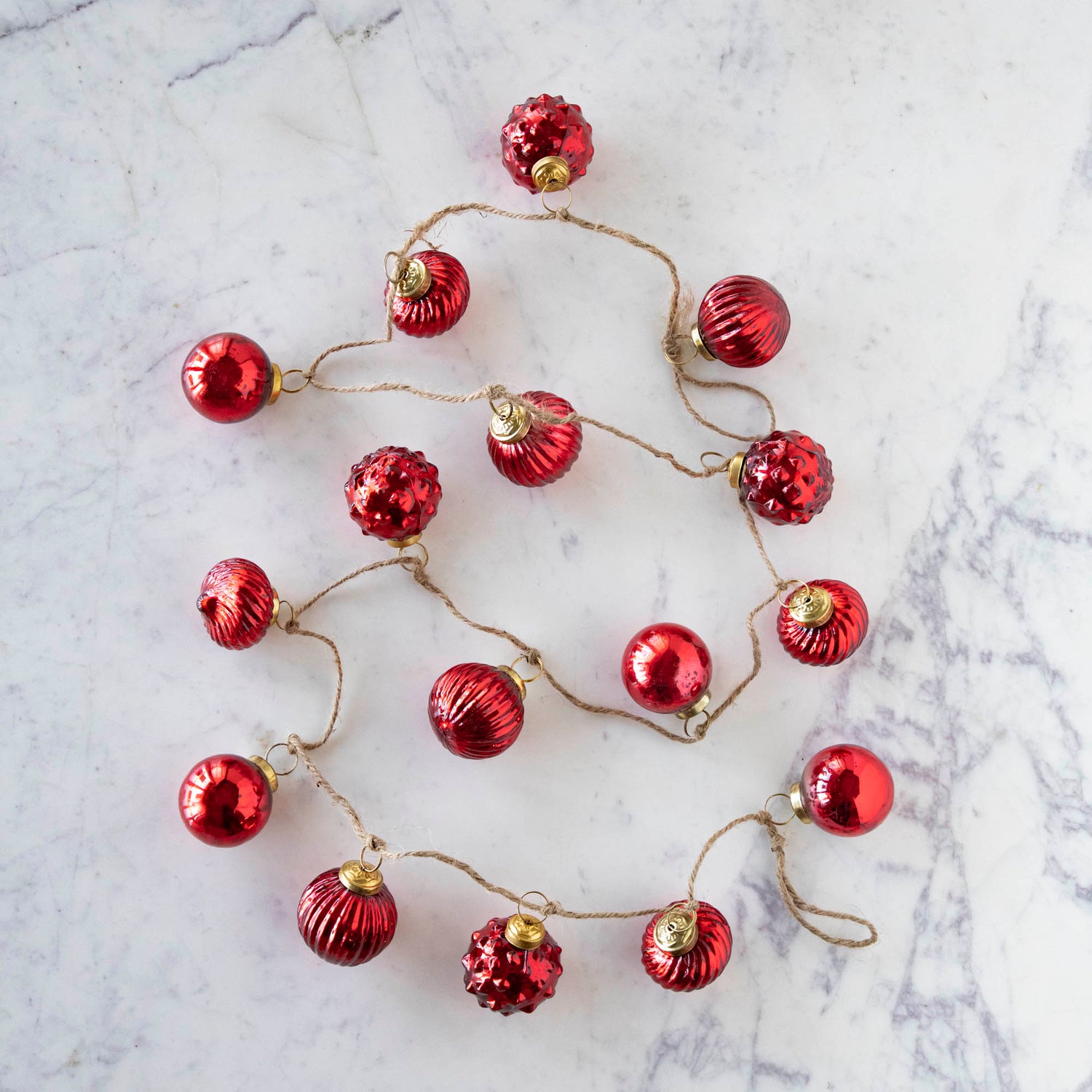 The Embossed Mercury Glass Ornament Garland on a marble table.