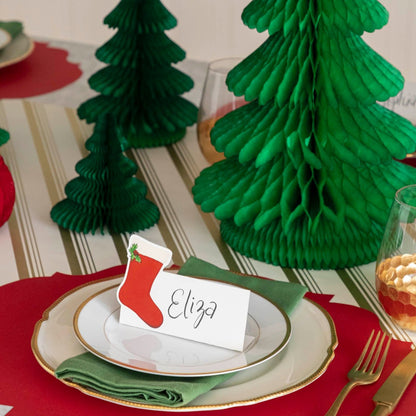 A Christmas table setting with honeycomb trees in behind a place setting.