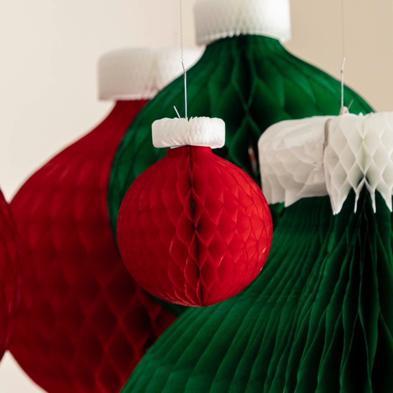 A small, red Honeycomb Classic Ornament hanging amongst large honeycomb classic ornaments.