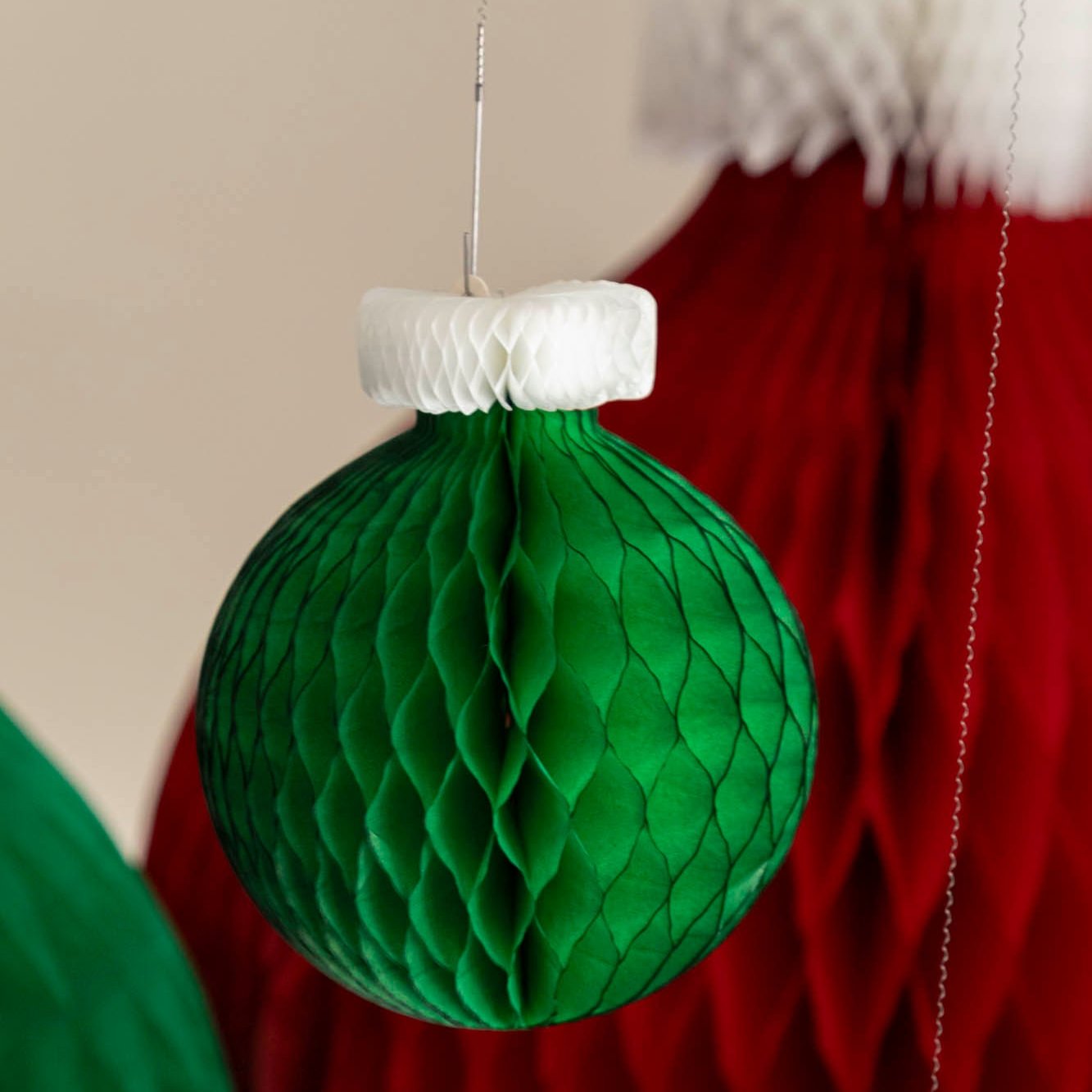 A small, green Honeycomb Classic Ornament hanging from the ceiling.