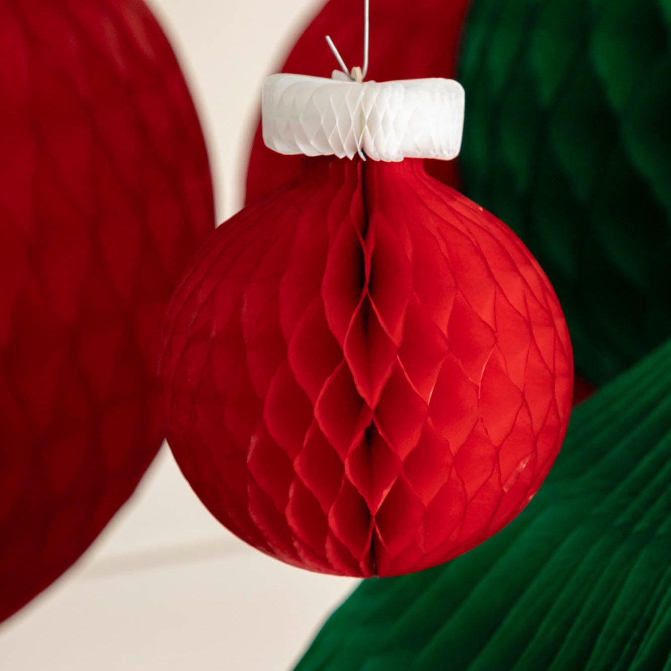 A small, red Honeycomb Classic Ornament hanging from the ceiling.