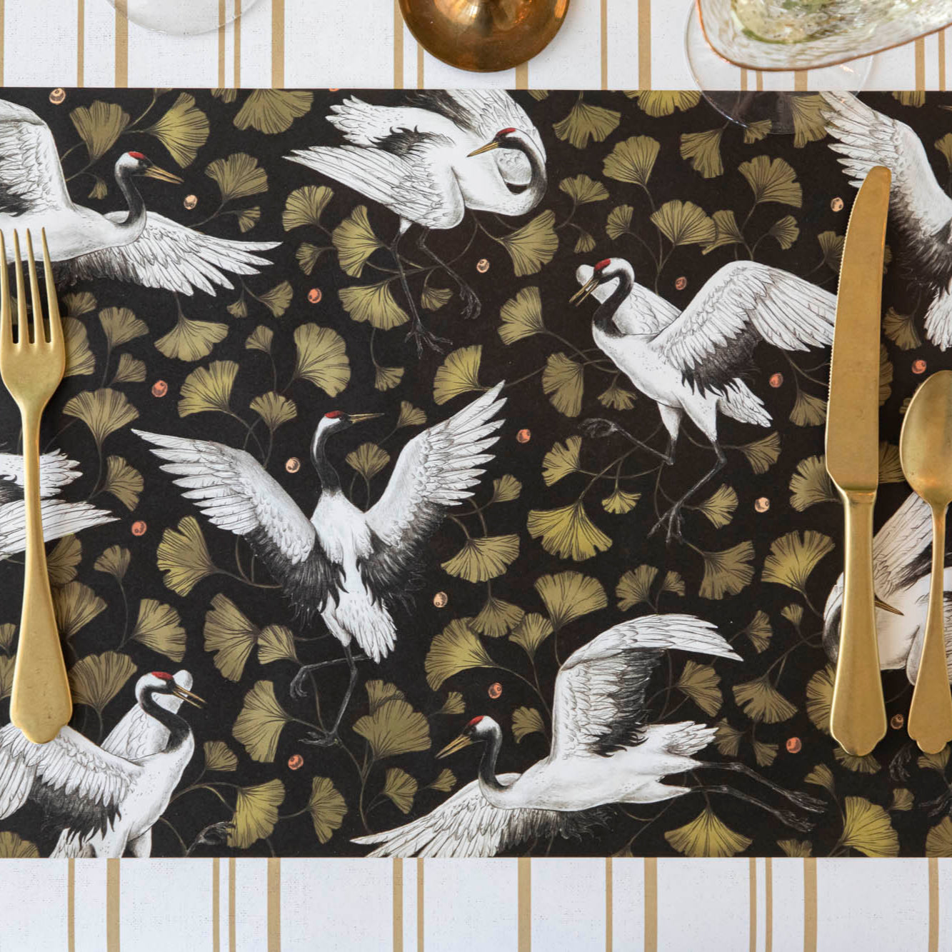 Crane Dance Placemat with gold flatware on top.