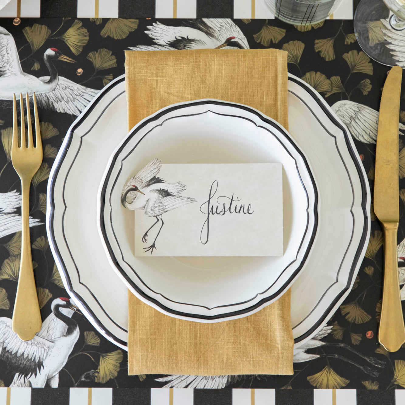 Crane Dance Place Card with &quot;Justine&quot; written on it, on an elegantly styled place setting for one.