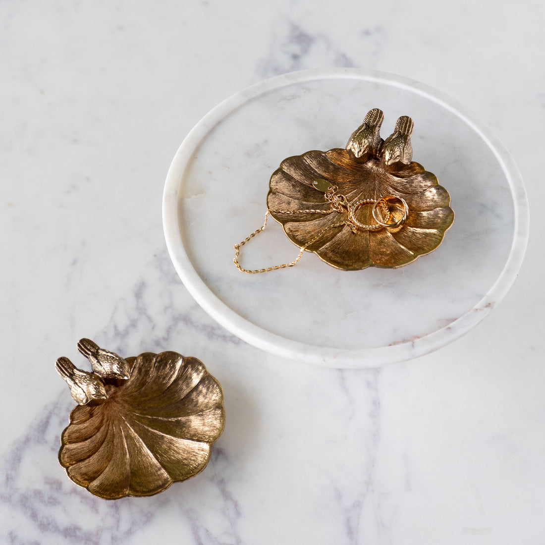 A Gilded Perch Pewter Jewelry Dish with jewelry in it and one empty.