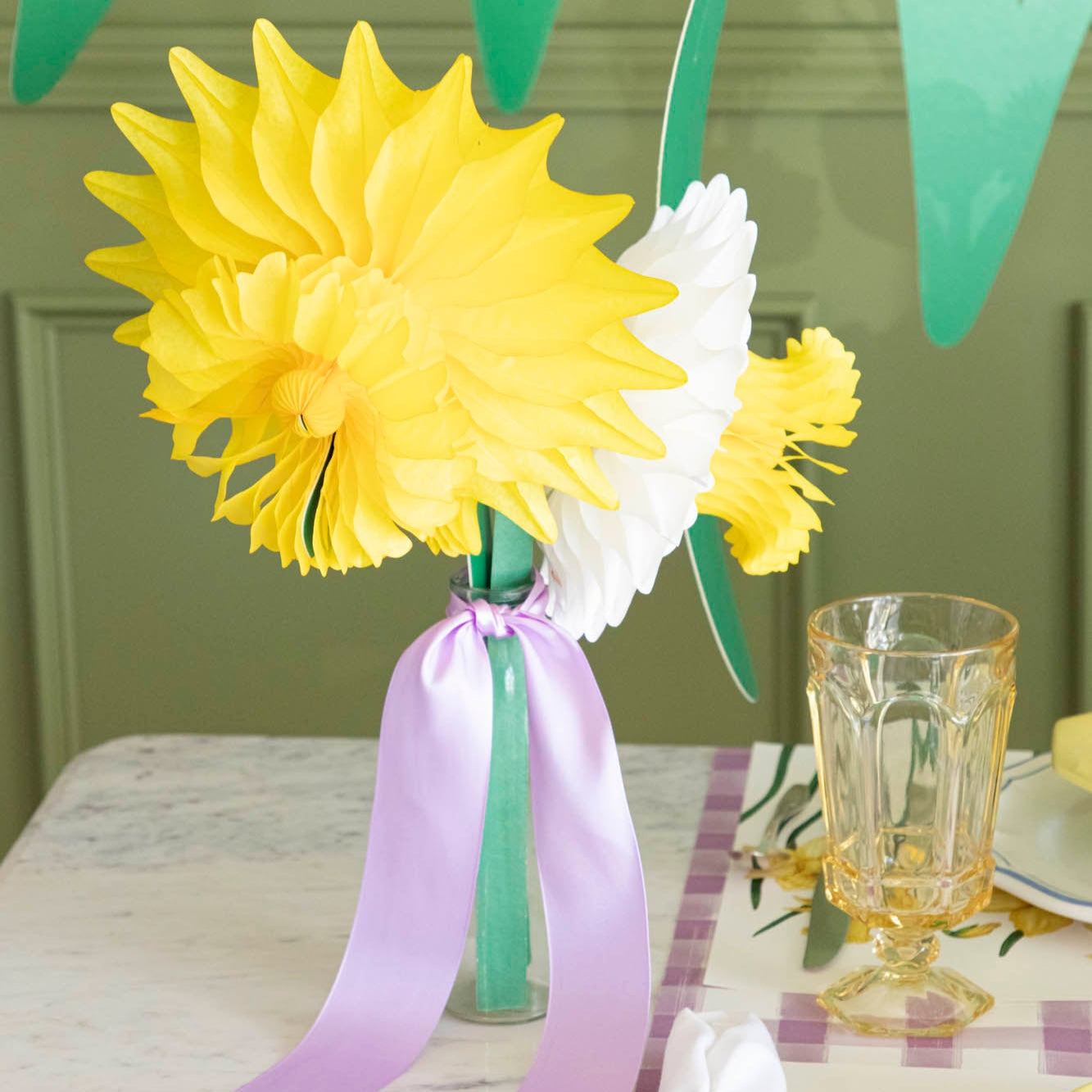 Medium and large Daffodil Honeycomb in a vase with a purple ribbon tied around it.