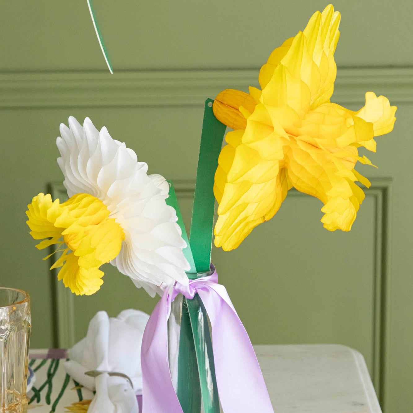 Medium and large Daffodil Honeycomb in a vase with a purple ribbon tied around it.