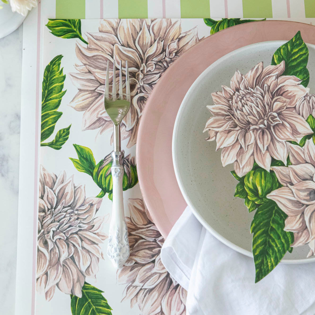 Dahlia Table Accent resting in the center of dinner plates on a place setting.