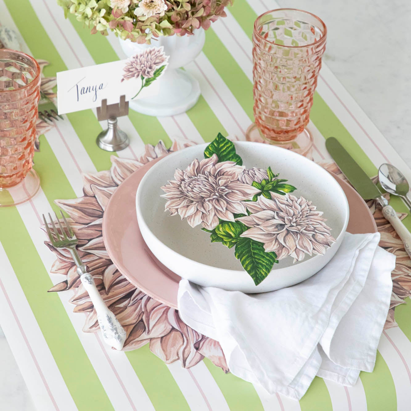 Dahlia Place Card with &quot;Tanya&quot; written in the white space, held up by the Chrome Place Card Holder, behind a place setting.