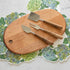 The Maple Oval Serving Board with a Teak & Stainless Cheese Server Set on top, with Hydrangea Serving Papers underneath.