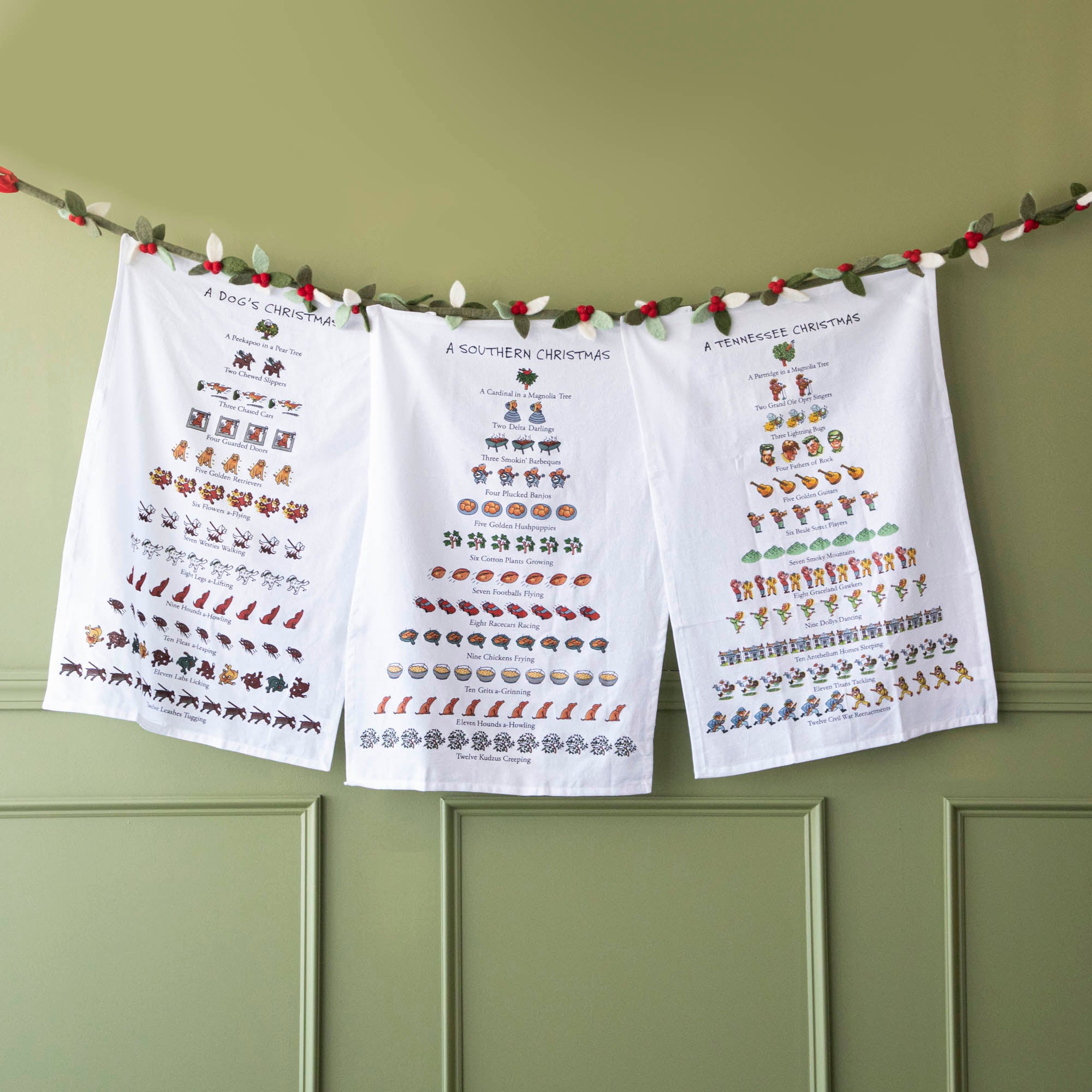 Christmas themed kitchen towels hanging on a felt berry garland.