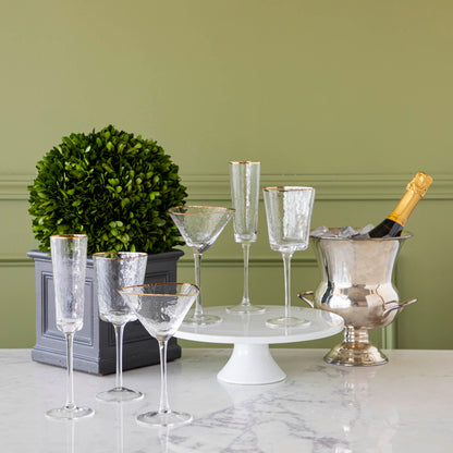 Hammered Glasses with Gold Rim styled with boxwood and champagne on ice in an ice bucket.