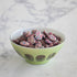 A Rialto Pale Sage Glass Bowl with Bang Candy Chocolate Buttons in it.