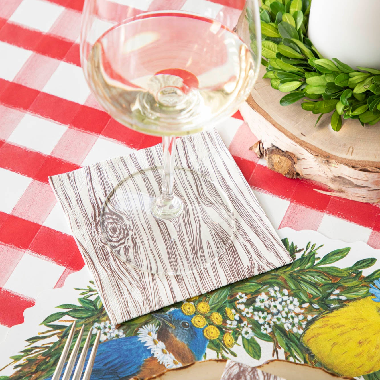 Oak Cocktail Napkin under a wine glass behind a place setting.